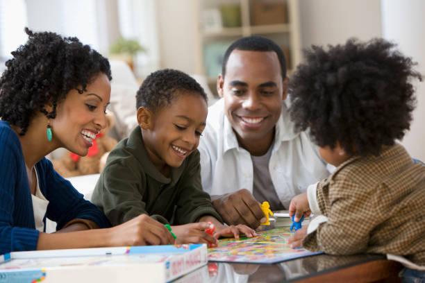 african american family playing board game together - board games stock pictures, royalty-free photos & images