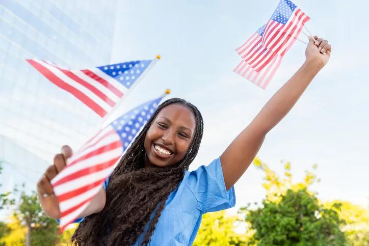 Young woman celebrating america with waving flags outdoors