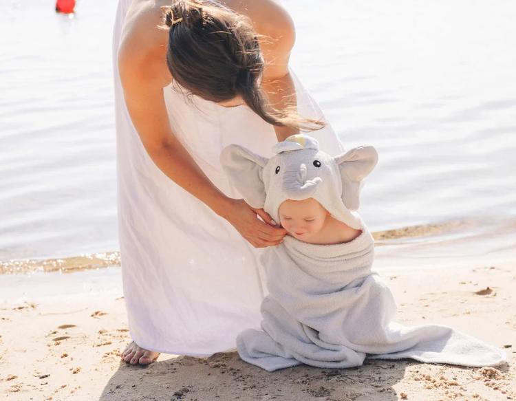 Mom playing with her baby by the lakeside while the baby stays cozy in a KeaBabies PlayPals Hooded Towel.