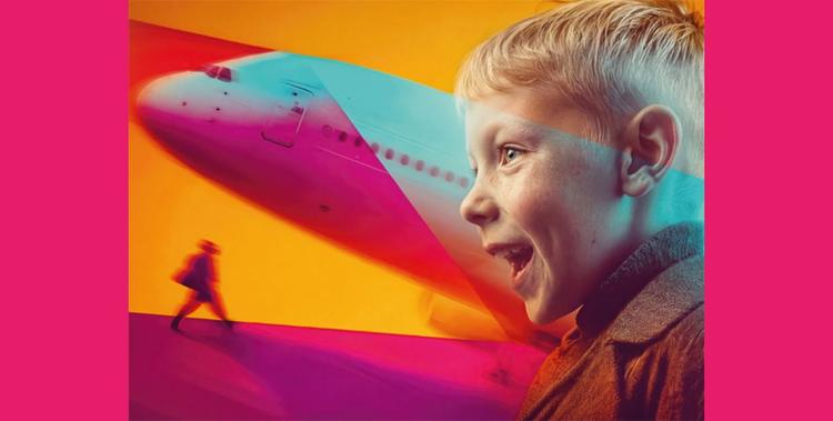  Eine Junge freut sich und hat den Mund weit offen im Hintergrund ist die Spitze eines Flugzeugs zu sehen