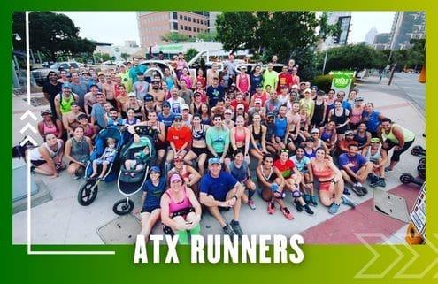A large, diverse group of runners from the Buda Running Club poses together outdoors on a city sidewalk. Some have strollers, and all wear athletic clothing. The text 