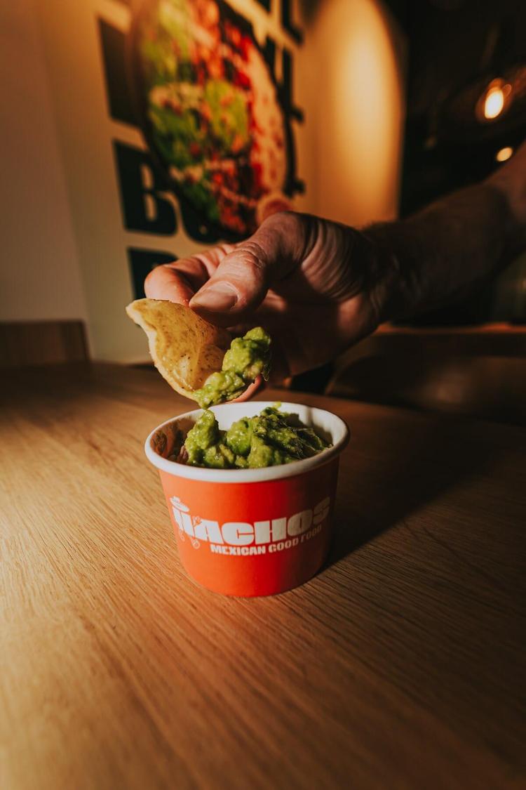 Une chips trempée dans un pot de guacamole fait maison, chez Nachos à Mérignac