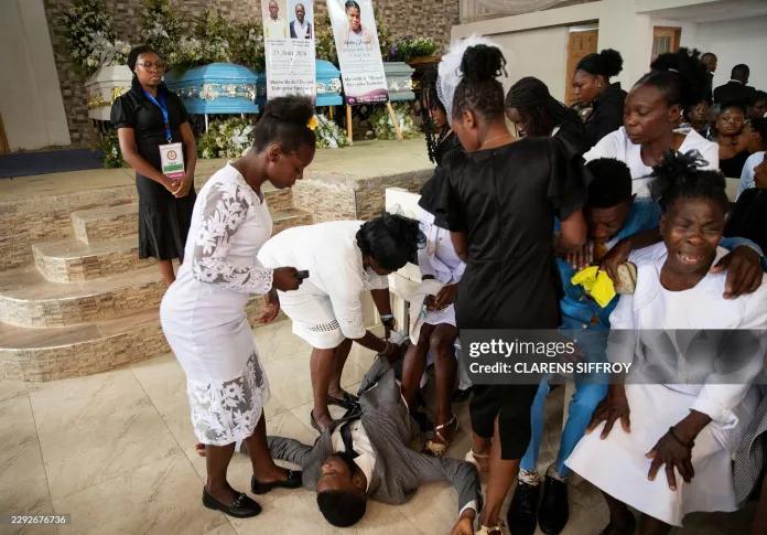 An overwhelmed man is attended to as people attend a collective funeral service for more than twenty people killed by armed gangs last week in Kenscoff, a neighborhood near Port-au-Prince, on September 2, 2026.