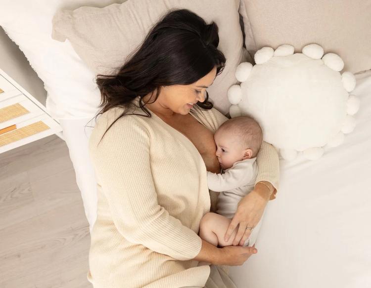 Mom and baby lying in bed together during a comfortable breastfeeding session