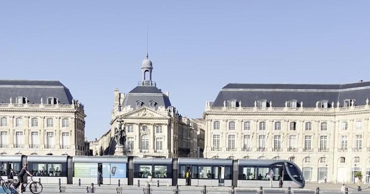 Place de la Bourse et tramway au bord du Miroir d'eau à Bordeaux sous un ciel bleu