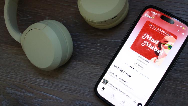 audible app open on phone laying next to headphones