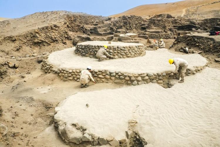 Archaeologists work on a circular stepped platform
