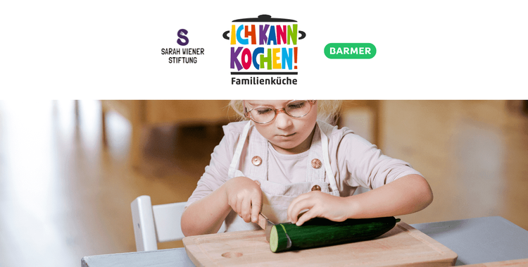  Kinder schneidet mit dem Messer eine Salatgurke, die auf einem Holzbrett liegt.