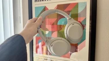 person holding silver sony headphones in front of picture