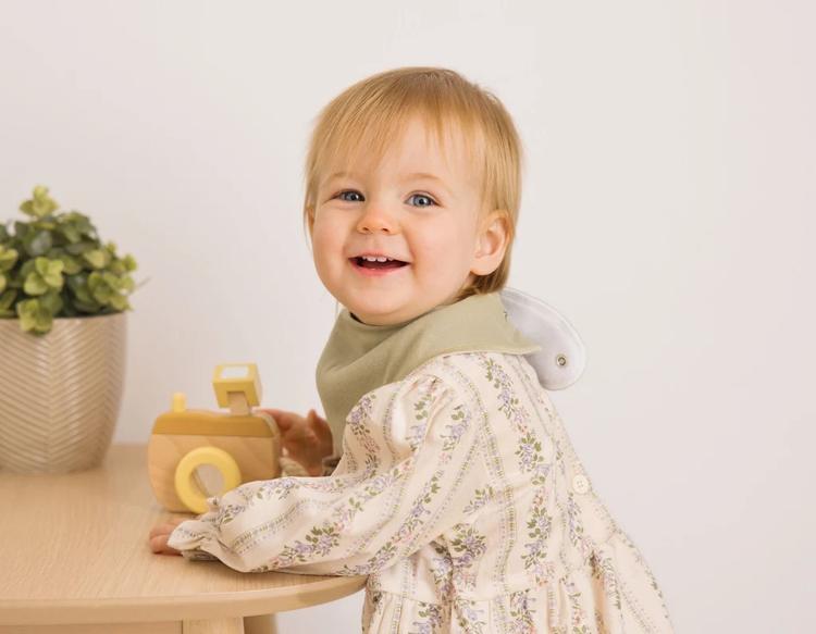 A young child playing with her toy while staying dry and comfortable in a bandana bib.
