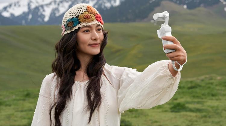 A woman holding up an Insta360 Luna Ultra to film herself.
