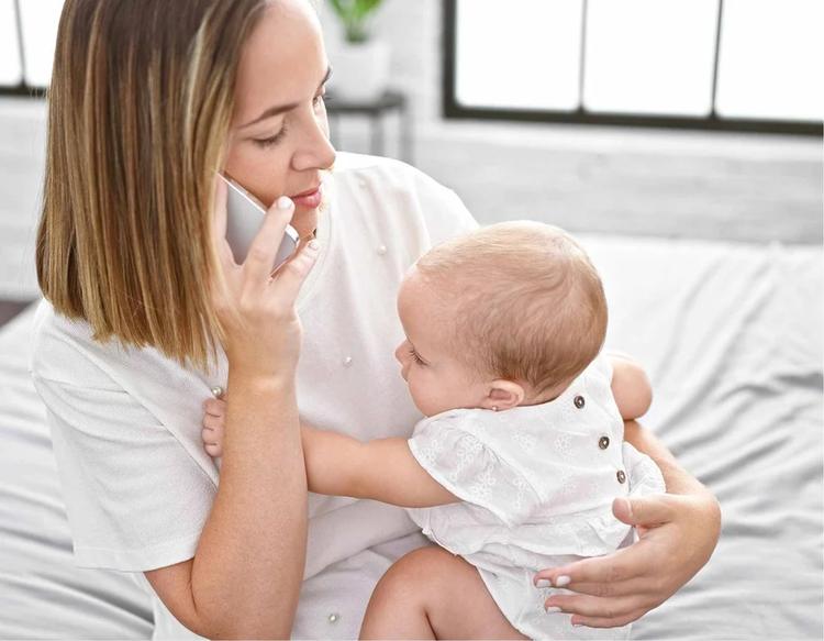 Mom holding her baby while talking on the phone as they prepare for bedtime.