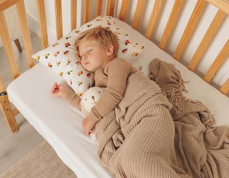 Toddler sleeping peacefully with a soft pillow in a cozy and calm bedtime setting.