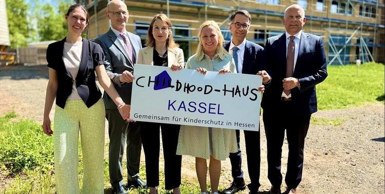  Ministerin Stolz mit weiteren Menschen mit einem Schild in der Hand: Childhood-Haus Kassel