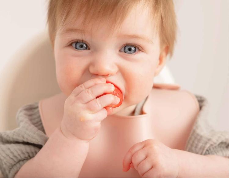 Baby eating a strawberry as a healthy finger food snack.