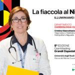 Smiling female doctor in a white coat with a stethoscope holds a yellow folder, beside a colorful abstract background and Italian event text on the right.