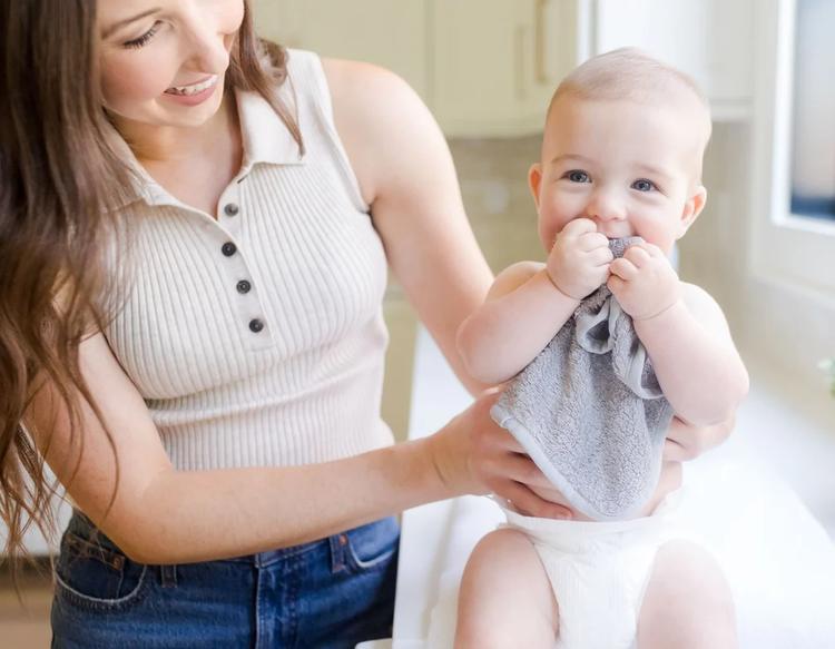 Baby holding a KeaBabies Deluxe Baby Washcloth, a soft, gentle, and multi-purpose cloth designed for everyday baby care, bath time, and feeding routines.