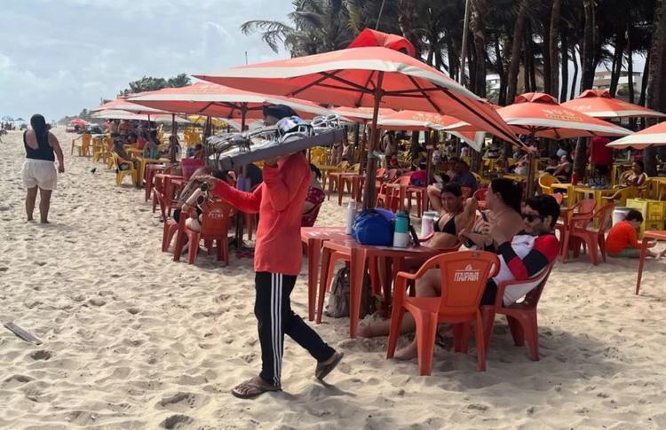 Ambulante vende óculos na Praia do Futuro: trabalho sem infraestrutura de apoio e com calor cada vez mais extremo (Foto: Lavínia Fonseca)