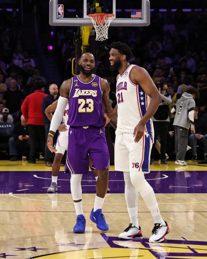 Joel Embiid and LeBron James smile as they talk on the court.