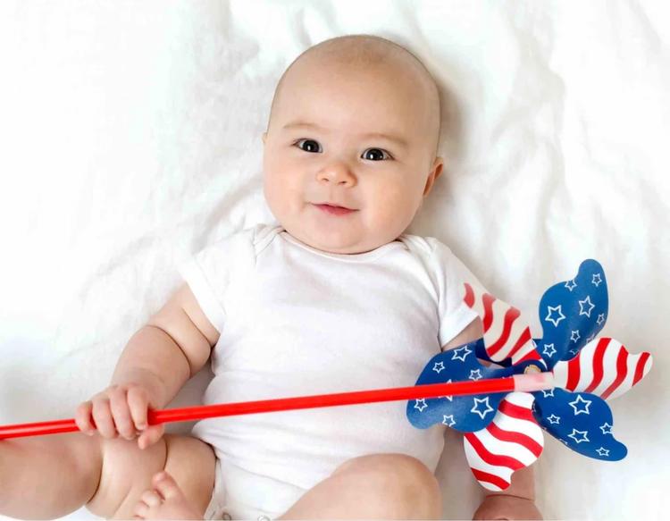 Baby girl holding a pinwheel designed like the US flag.