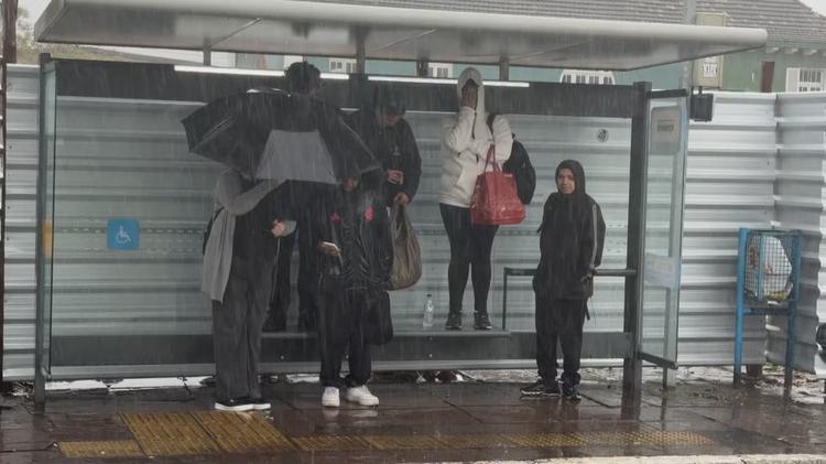 FOTO: passageiros sobem em banco para se proteger de chuvarada em parada de ônibus de Porto Alegre