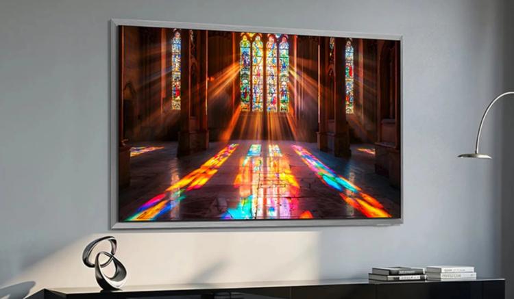 Samsung S95H TV mounted on wall above TV stand