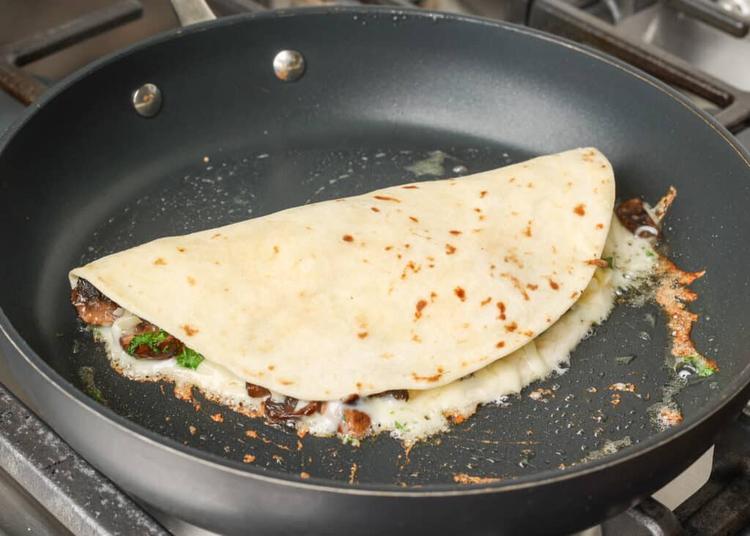 folded quesadilla with melting cheese in skillet