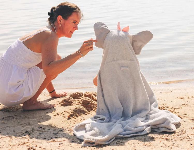 Mom with a toddler wrapped in a PlayPals Hooded Towel playing by the lakeside on a sunny day.