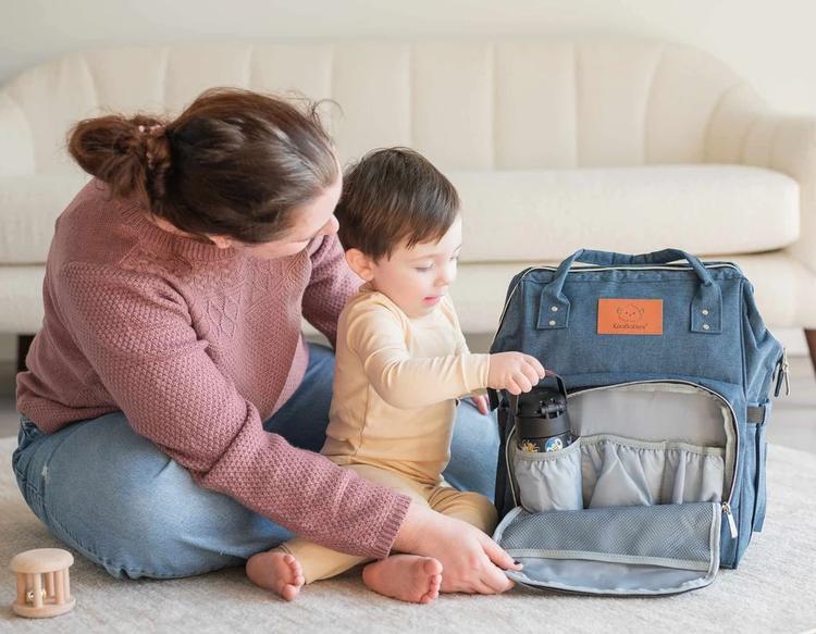 Mom helping her toddler set up a bag and pack essential items, promoting organization, independence, and daily routine preparation.