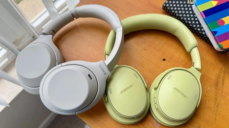 sony and bose headphones on desk next to notebook and pencil case