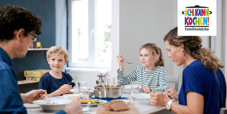  Familie mit Vater, Mutter und zwei Kindern sitzt am Tisch beim Essen.