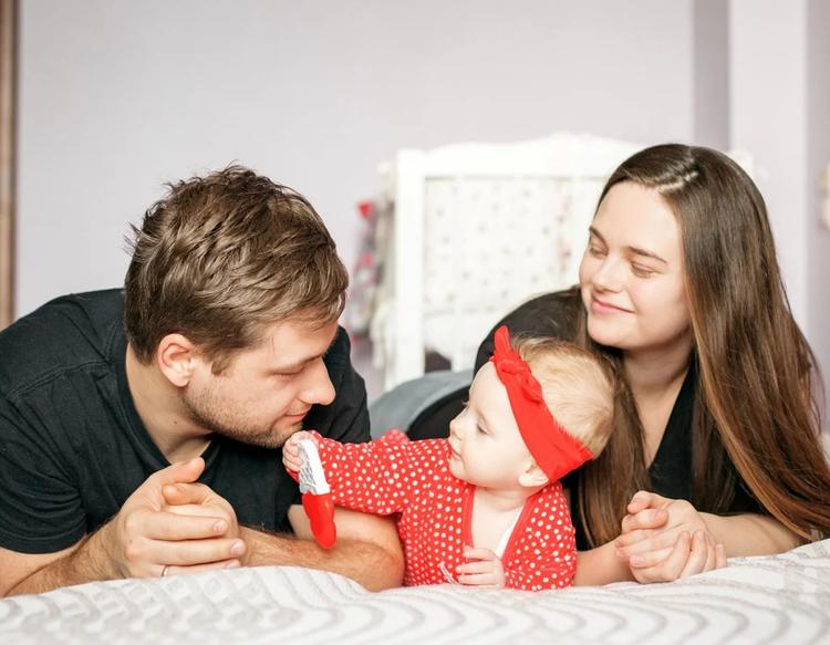 Mom, dad, and newborn baby enjoying playtime together at home, bonding through a warm family moment.